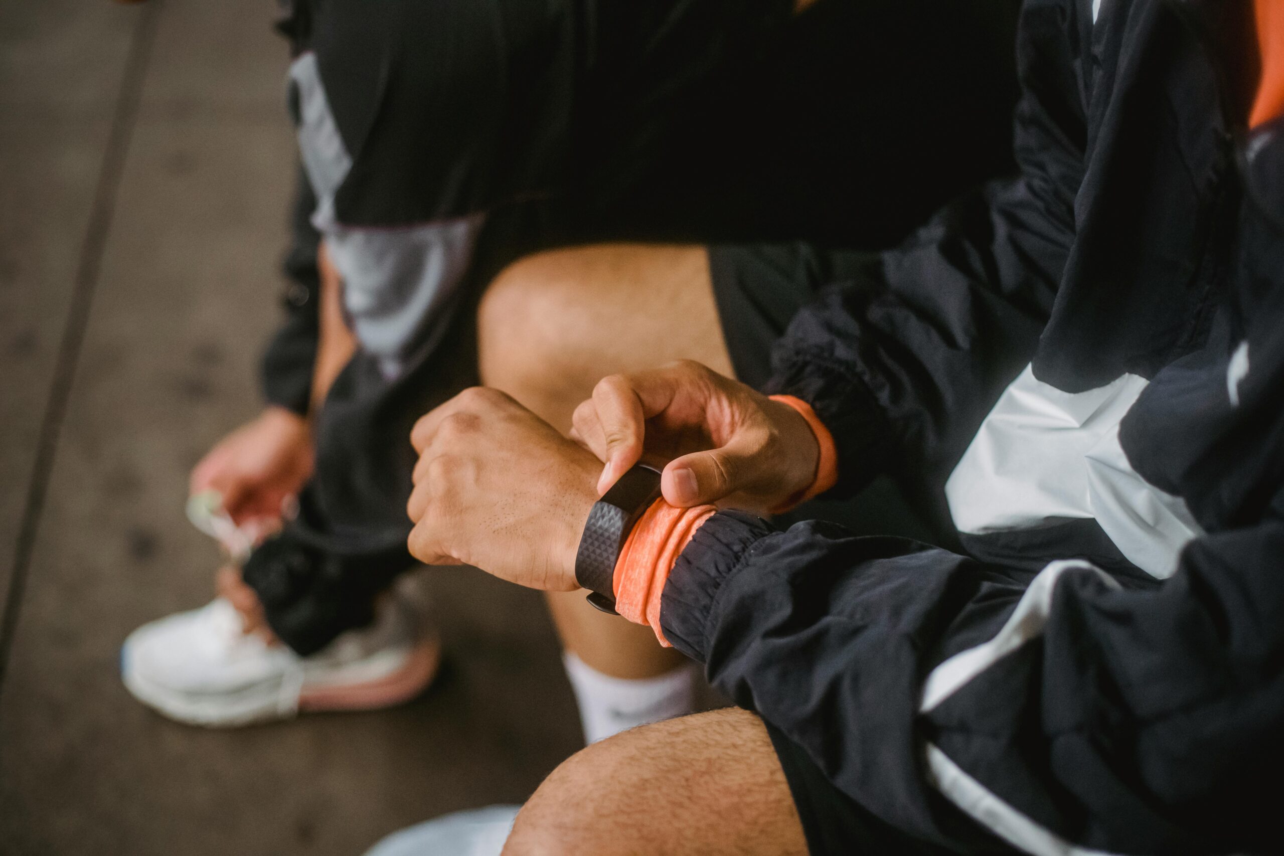 Close-up of a man in athletic wear adjusting a smartwatch, showcasing fitness and technology integration.