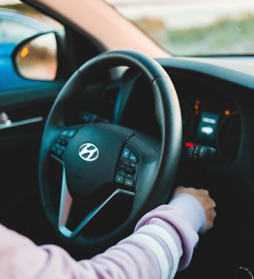 Crop unrecognizable person starting engine in contemporary auto near steering wheel in daylight