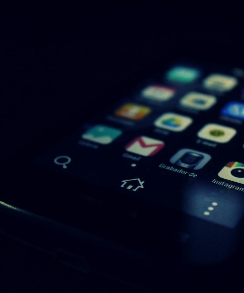 Dark-themed close-up of a smartphone screen highlighting various apps and touchscreen technology.